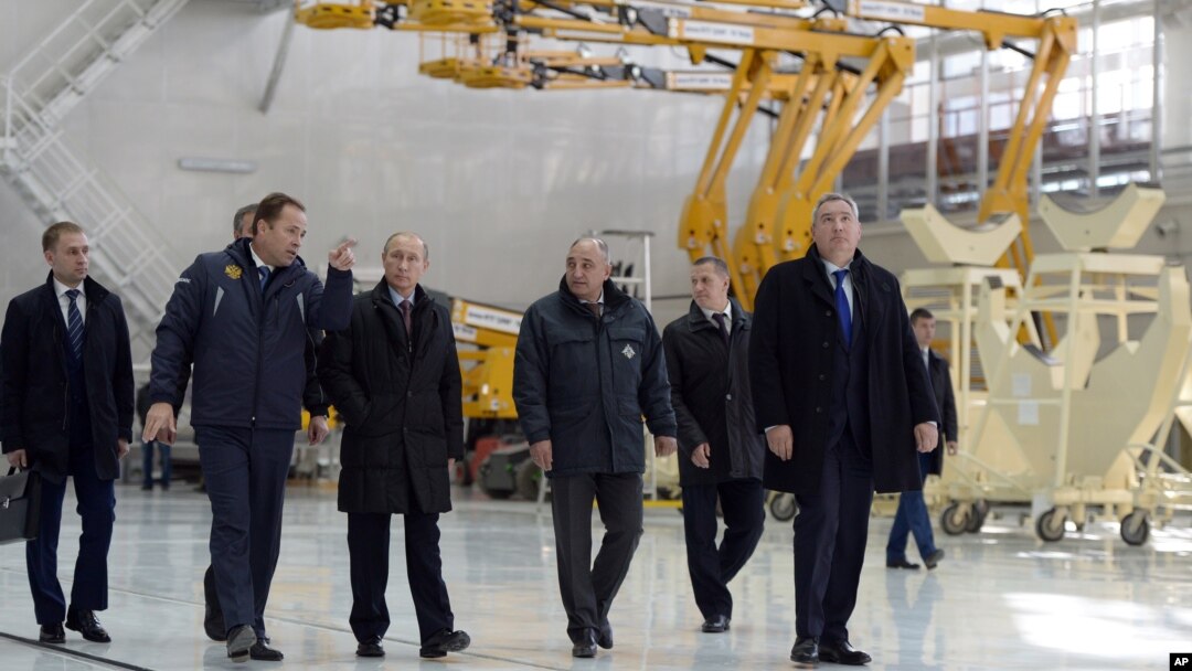 Russian President Vladimir Putin, third left, escorted by Russian Federal Space Agency head Igor Komarov, second left, walks through a working hall while visiting the Vostochny Cosmodrome near Uglegorsk, the city in eastern Siberia in the Amur region, Russia, October 14, 2015.