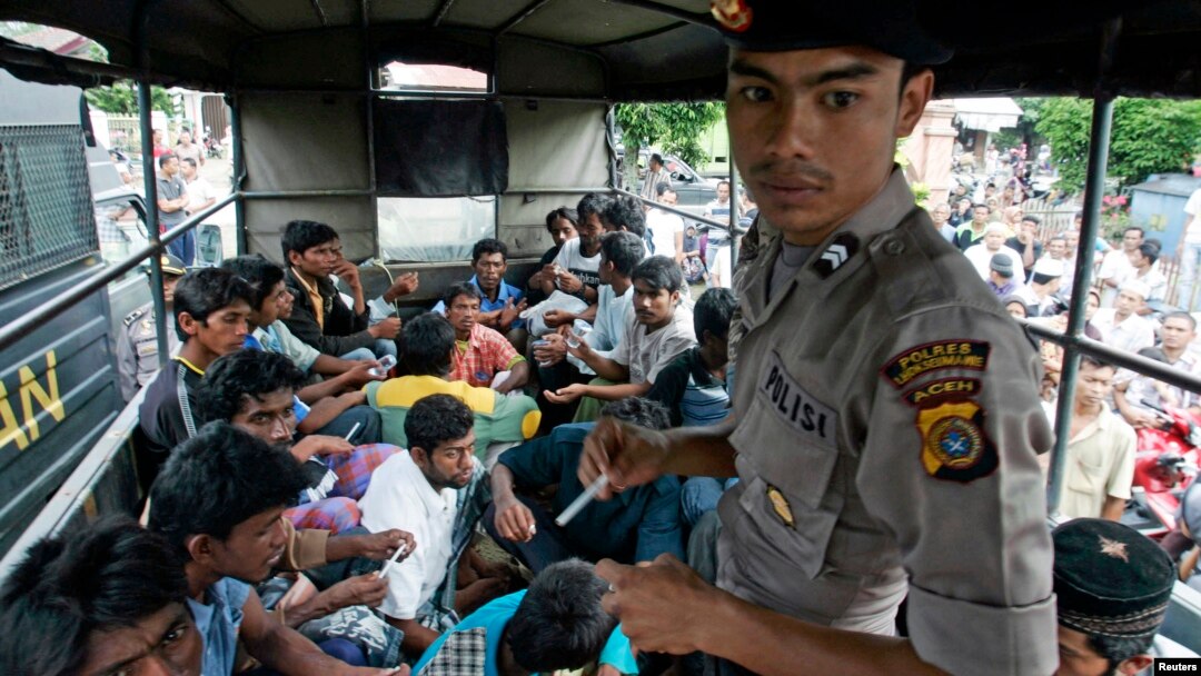 An Indonesian policeman guards ethnic Rohingya refugees from Myanmar as they wait inside a police truck for identification by immigration personnel in Lhokseumawe, Feb. 27, 2013. 