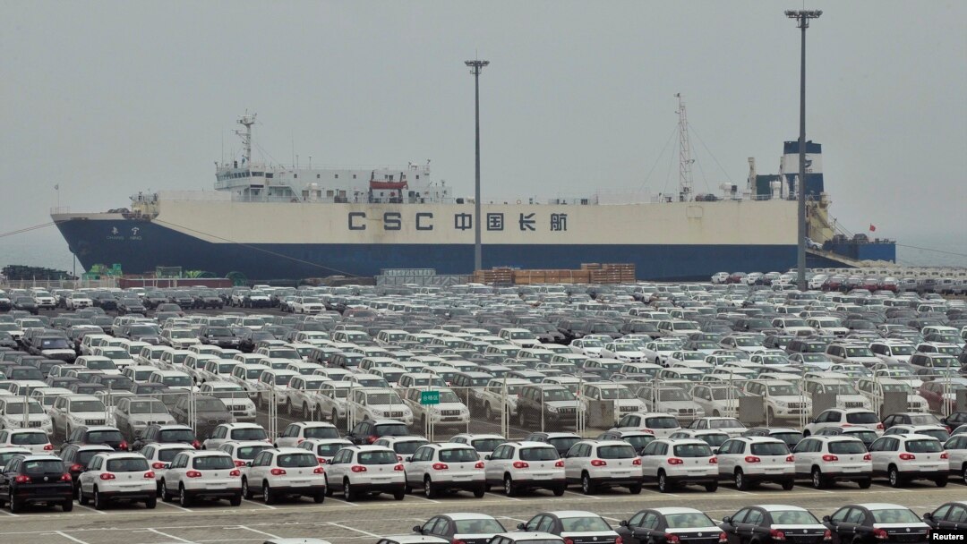 FILE - Newly-manufactured cars and a container ship are seen at Dayaowan port of Dalian, Liaoning province, June 10, 2012. 