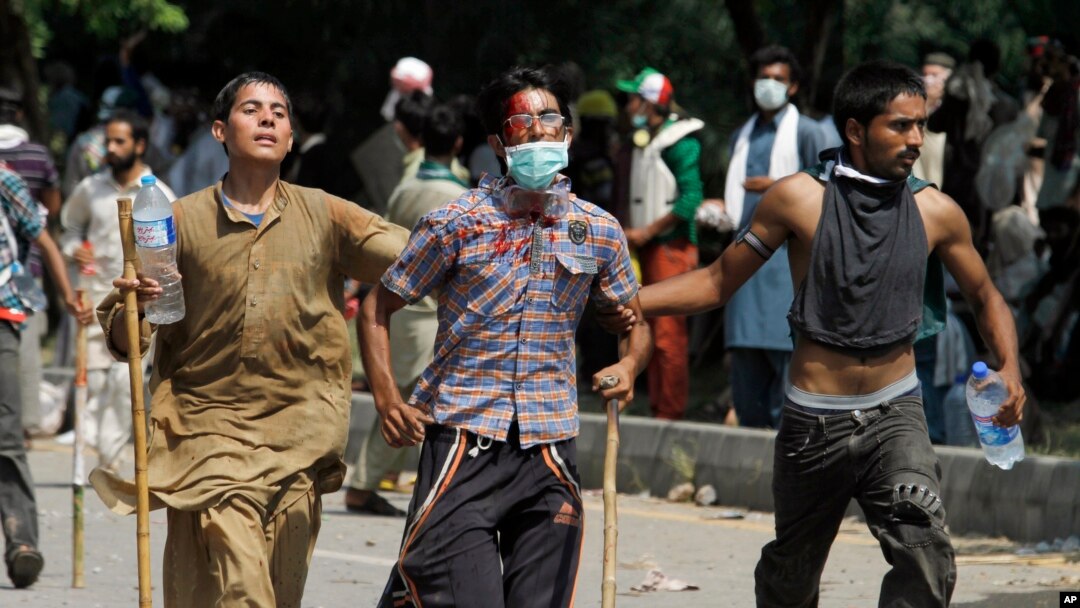Pakistani protesters help escort their injured colleague to an ambulance during a protest near prime minister's home in Islamabad, Sunday, Aug. 31, 2014.