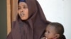 FILE - A Somali woman, who was sentenced to a year in jail after she told a reporter she was raped by security forces, holds her baby at the court house in Mogadishu, March 3, 2013.