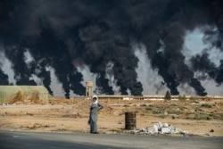 Smoke billows from burning tires to decrease visibility for Turkish warplanes on the outskirts of the town of Tal Tamr, Syria, along the border with Turkey in the northeastern Hassakeh province.