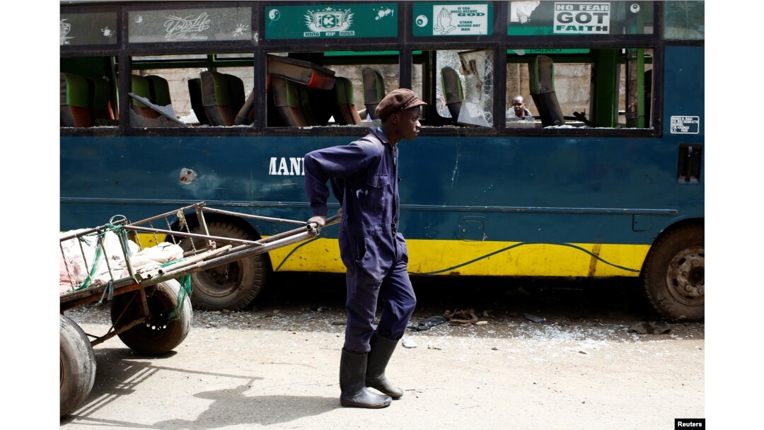 A man pulling a cart passes next to a bus vandalized during the latest protests in Mathare, Nairobi, Kenya, August 14, 2017.