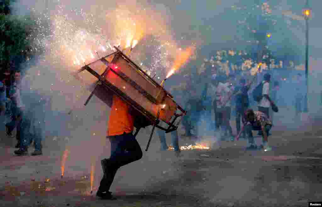 A man runs with a "toro encuetado" — a structure resembling a bull and emitting exploding firecrackers — during celebration in honor of the Virgin Mary in Leon, Nicaragua, Aug.14, 2018.