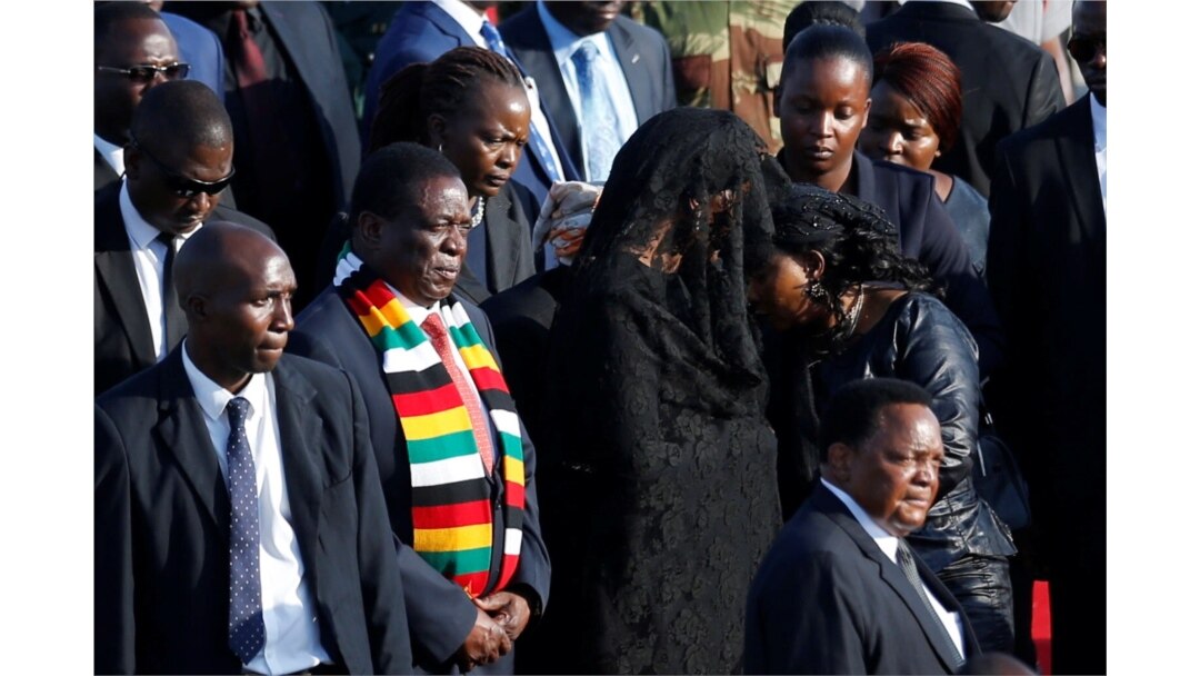 Zimbabwean President Emmerson Mnangagwa stands next to Grace Mugabe, after receiving the body of her husband, former Zimbabwean President Robert Mugabe in Harare, Sept. 11, 2019.
