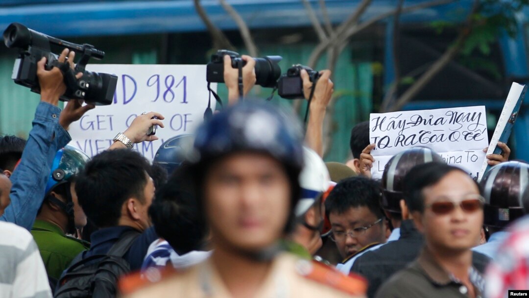 Police and security personnel film protesters holding placards which read, "Haiyang 981 oil rig get out of Vietnam (left)" and "Take China to the international court" (right) during an anti-China protest in Vietnam's southern Ho Chi Minh city May 18, 2014.