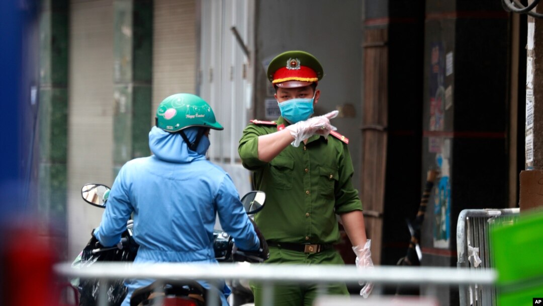 A police officer talks to a woman at the barricaded entrance of an alley where one of its residents is suspected to have COVID-19 in Hanoi, Vietnam, July 29, 2020.