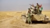 A peshmerga tank crew rests outside Bashiqa, Iraq. (J. Dettmer/VOA)