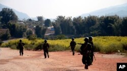 FILE - Myanmar army soldiers carrying weapons patrol on a road as part of operations against ethnic rebels, in Kokang, northeastern Shan State, more than 800 kilometers (500 miles) northeast of Yangon, Myanmar.