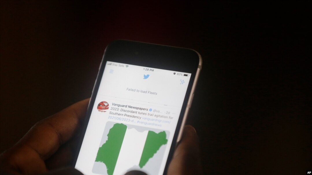 FILE - A man uses his mobile phone to read news on Twitter inside an office in Lagos, Nigeria, June 7, 2021.