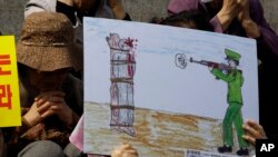FILE - A North Korean defector reacts next to a drawing depicting a public execution of a North Korean soldier during a human rights rally in Seoul, South Korea, April 14, 2011. 