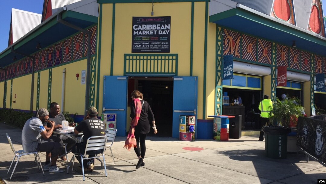 Customers sit outside the Caribbean Marketplace in Little Haiti, Miami, Florida. (Photo: S. Lemaire / VOA) 