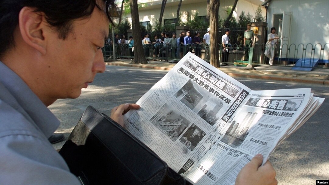 FILE - A Chinese visa applicant reads a Beijing newspaper as he waits outside the U.S. Embassy.