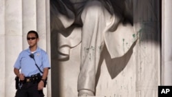 A U.S. Park Police officer stands guard next to the statue of Abraham Lincoln at the memorial in Washington, July 26, 2013. The memorial was closed to visitors after someone splattered green paint on the statue and the floor area. 