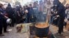 A volunteer stirs a food pot as Palestinians wait to collect humanitarian aid portions, in al-Shati camp near Gaza City on Dec. 26, 2024.