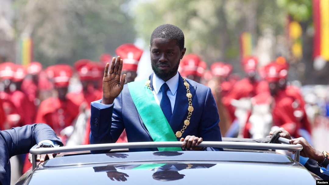 Senegalese President Bassirou Diomaye Faye waves to supporters from a car after taking the oath of office as president during his inauguration ceremony near Dakar on April 2, 2024.