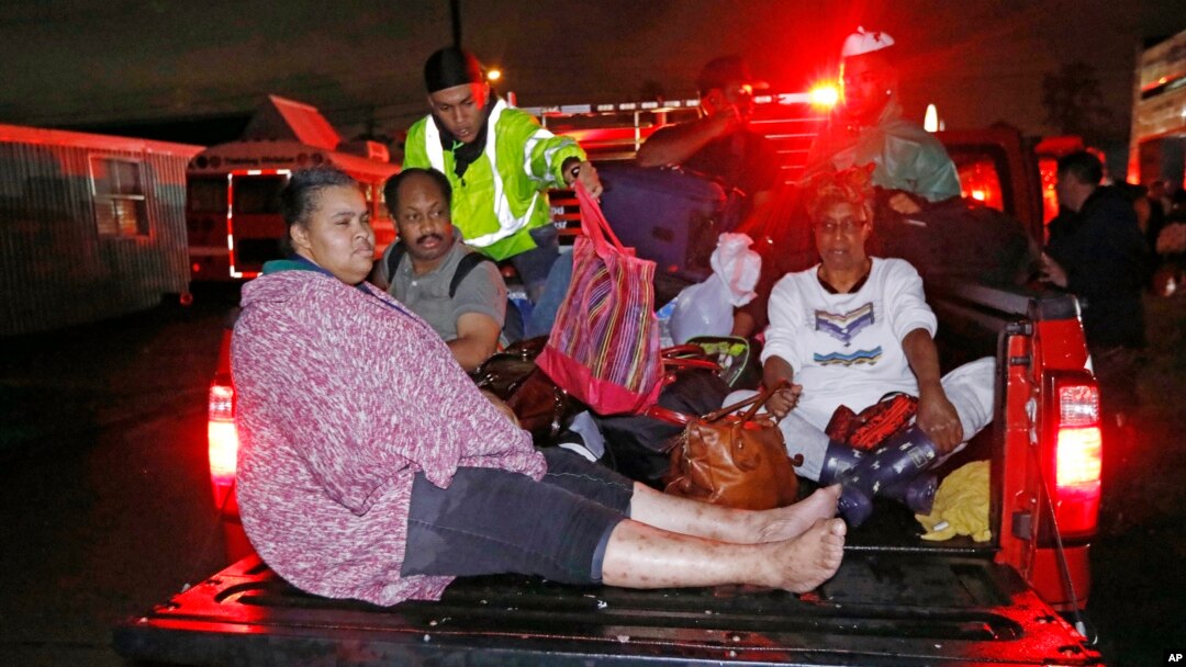 Residents ride in the bed of an emergency vehicle carrying them to safety following flooding to their homes late Monday night, Aug. 28, 2017 in Lake Charles, La.
