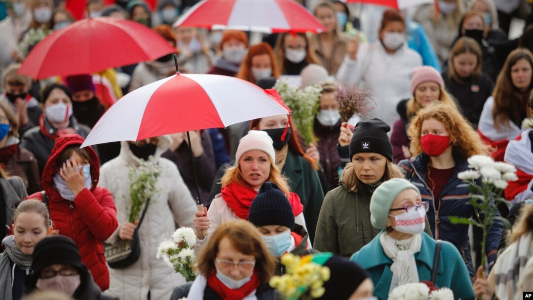 Belarusian women with umbrellas in the colors of the old Belarusian national flag take part in an opposition rally to protest the official presidential election results in Minsk, Belarus, Oct. 24, 2020.