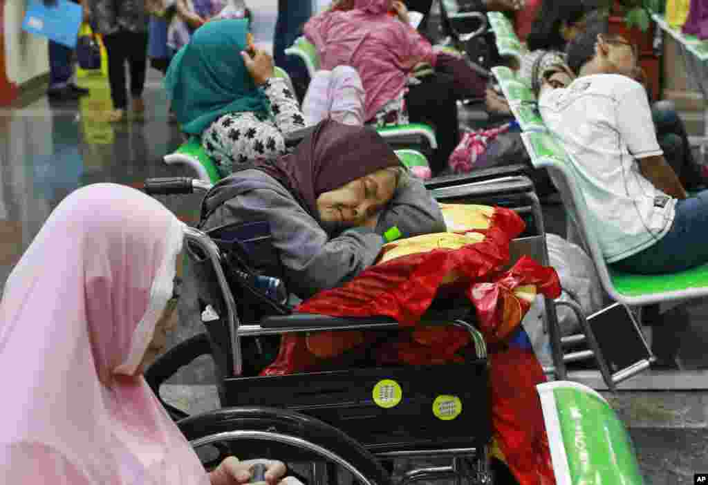 A patient takes a nap on her wheelchair as she waits with others at the registration desk at Dharmais Cancer Hospital in Jakarta, Indonesia as the hospital's information system is affected by the ransomware. Global cyber chaos was spreading as companies booted up computers at work following the weekend's worldwide cyberattack.