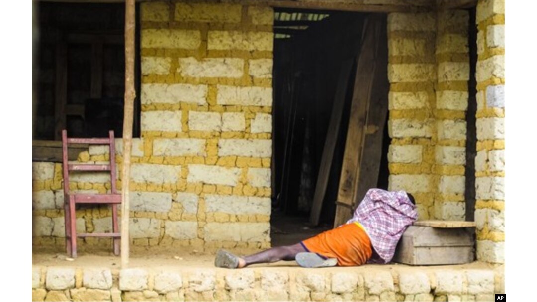 FILE - A man suffering from the Ebola virus lies on the floor outside a house in Port Loko Community, situated on the outskirts of Freetown, in Sierra Leone, Oct. 21, 2014.