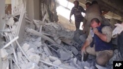 This image taken Sept. 30, 2015 posted on the Twitter account of Syria Civil Defence, also known as the White Helmets, a volunteer search and rescue group, shows the aftermath of an airstrike in Talbiseh, Syria.