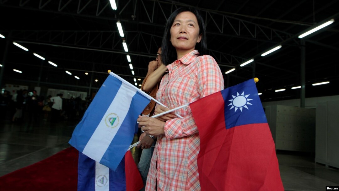 A Taiwanese citizen living in Managua holds Nicaragua's flag and Taiwan's flag as she waits for arrival of Tawain's President Tsai Ing-wen at the textile industrial park in Managua, Nicaragua Jan. 10, 2017. 