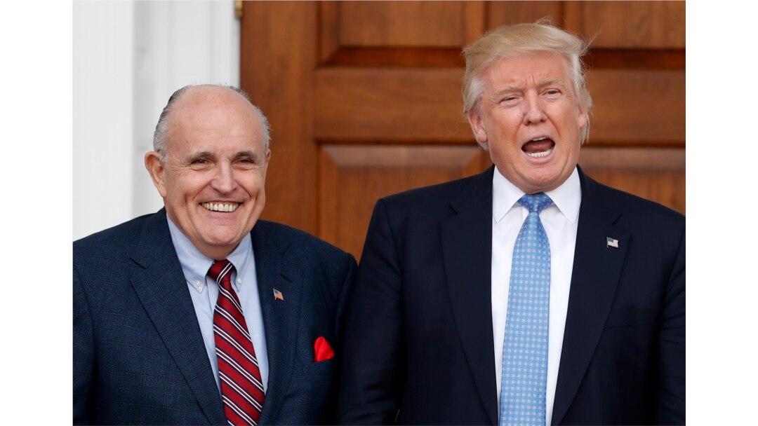 FILE - Then-President-elect Donald Trump calls out to media as he and former New York City Mayor Rudy Giuliani pose for photographs at the Trump National Golf Club, in Bedminster, New Jersey, Nov. 20, 2016.