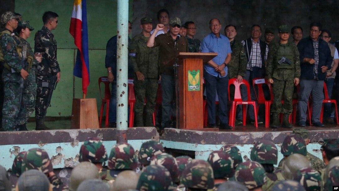President Rodrigo Duterte (center, at podium) clenches his fist as he declares the liberation of Marawi after an almost five-months long battle to oust Islamic State fighters from the city, in Marawi, Philippines, Oct. 17, 2017.