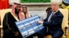 President Donald Trump shows a chart highlighting arms sales to Saudi Arabia during a meeting with Saudi Crown Prince Mohammed bin Salman in the Oval Office of the White House, March 20, 2018, in Washington.