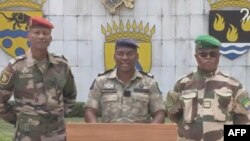Msemaji wa Kamati ya Mpito na Urejeshaji wa Taasisi (CTRI), Kanali Ulrich Manfoumbi Manfoumbi (kati) akisoma taarifa kwenye televisheni. AFPTV