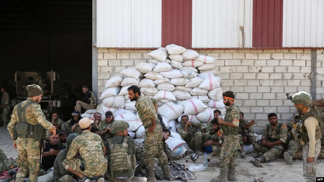 Turkish soldiers and Turkish-backed Syrian rebels gather near the Syrian border town of Ras al-Ayn, Oct. 12, 2019, as Turkey and its allies continued their assault on Kurdish-held border towns in northeastern Syria.