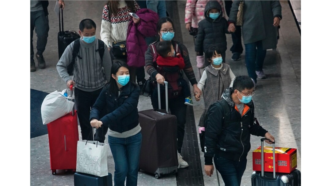 Passengers wear protective face masks arrive at the high speed train station in Hong Kong, Jan. 28, 2020. Hong Kong's leader has announced that all rail links to mainland China will be cut starting Friday.