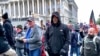 A man (center in black coat) identified by U.S. federal prosecutors as Shane Jason Woods of Auburn, Illinois. is seen in a frame grab from video shot during the Jan. 6, 2021 assault on the U.S. Capitol, moments before attacking members of the news media. 
