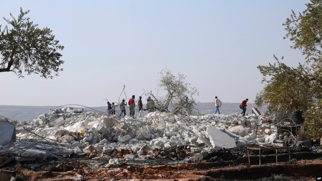 FILE - People look at a destroyed houses near the village of Barisha, in Idlib province, Syria, Oct. 27, 2019, after an operation by the U.S. military which targeted Abu Bakr al-Baghdadi, the shadowy leader of the Islamic State group.
