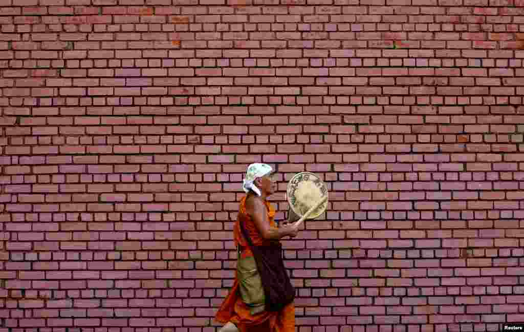 A monk plays a traditional musical instrument as he walks along a street in Colombo, Sri Lanka.