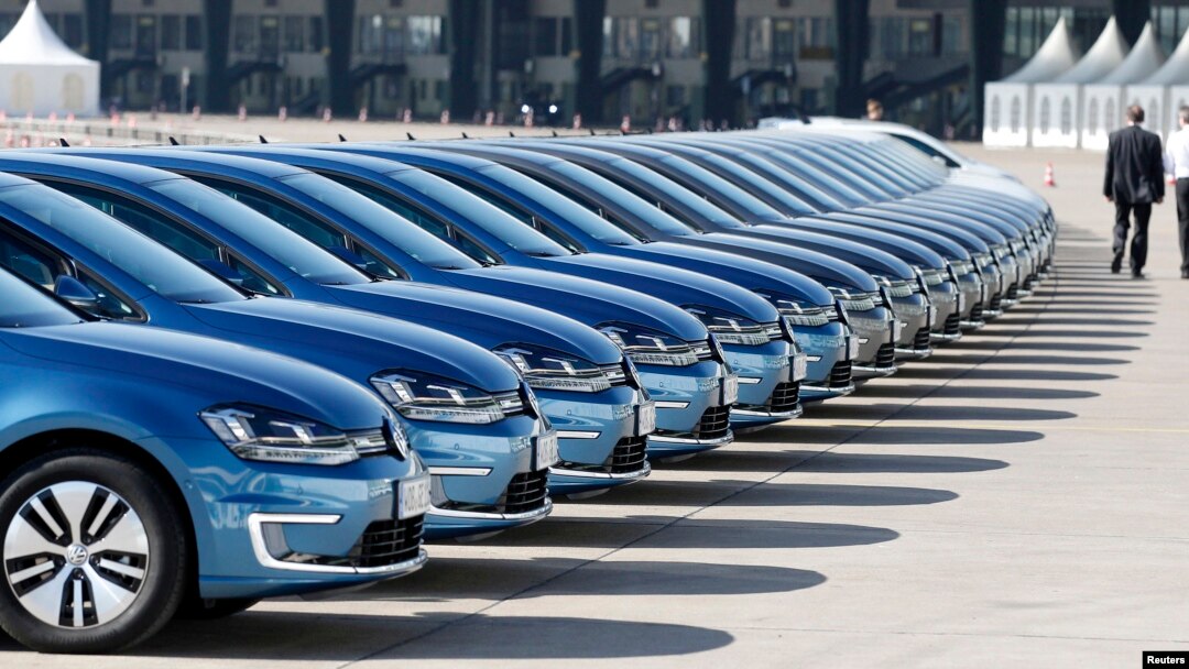 FILE - People walk past row of Volkswagen e-Golf cars during the company's annual news conference in Berlin, March 13, 2014.