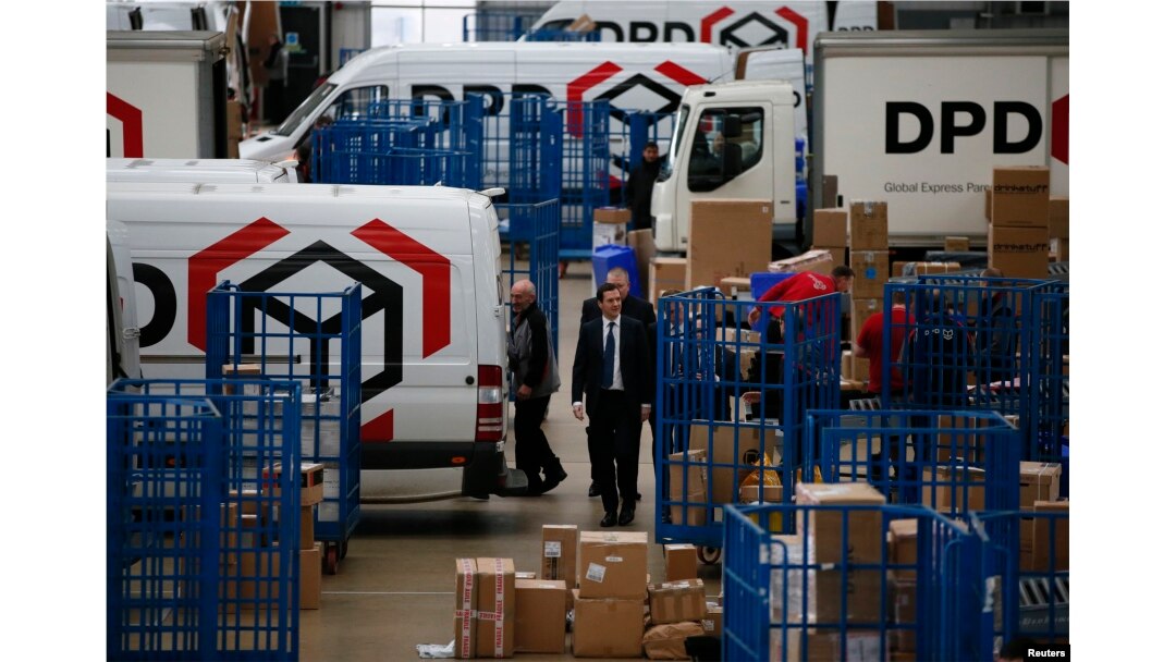 FILE - Britain's Chancellor of the Exchequer George Osborne walks past delivery vans during a visit to the DPD parcels depot in Raunds, Britain, May 6, 2015.