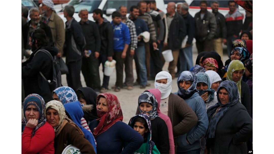 Syrians line up for food at a distribution center in the northwestern city of Afrin, Syria, during a Turkish government-organized media tour into northern Syria, March 24, 2018.