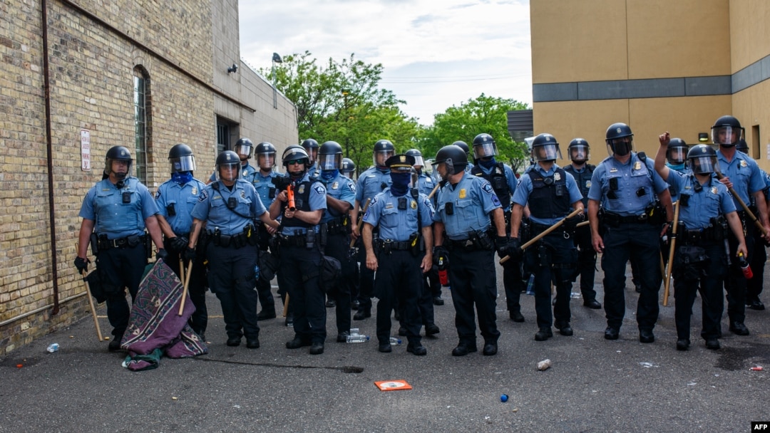 FILE - Minneapolis police officers stand in a line facing protesters demonstrating against the death of George Floyd, outside the 3rd Police Precinct in Minneapolis, Minnesota, May 27, 2020. 