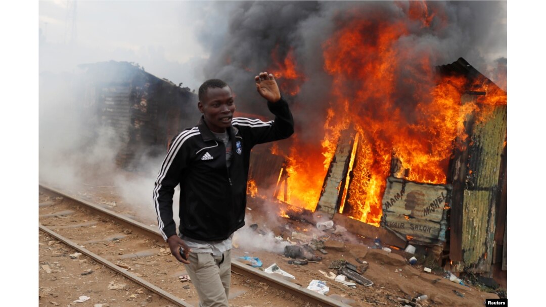 A supporter of opposition leader Raila Odinga runs past a burned shack, in Kibera slum, Nairobi, Kenya, Aug. 12, 2017.
