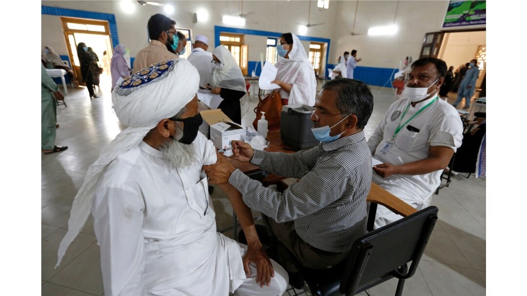 A teacher receives the first shot of the Sinovac coronavirus vaccine from a paramedics in a vaccination center at a school in Lahore, Pakistan, May 28, 2021.