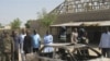 Bystanders gather around a burned car outside the Victory Baptist Church in Maiduguri, Nigeria, Saturday, Dec. 25, 2010.