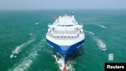 FILE - The Galaxy Leader cargo ship is escorted by Houthi boats in the Red Sea in this photo released Nov. 20, 2023. Because of Houthi attacks on Red Sea vessels, some shippers are starting to carry cargo by trucks driven through Saudi Arabia. (Houthi Military Media via Reuters) 