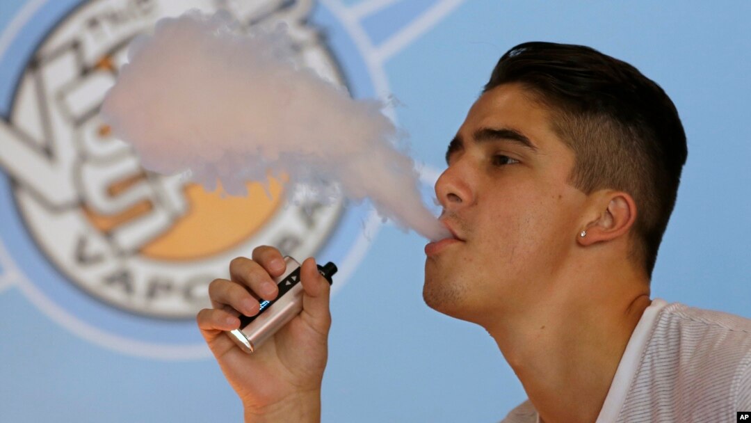 FILE - A smoker exhales vapor from an e-cigarette at the Vapor Spot, in Sacramento, California, in this July 7, 2015, photo.