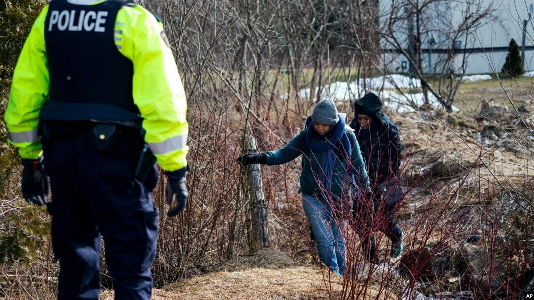 FILE - Two people who later indicated to officials they are from Sudan cross into Canada from Perry Mills, N.Y., near Hemmingford, Quebec, Feb. 26, 2017.