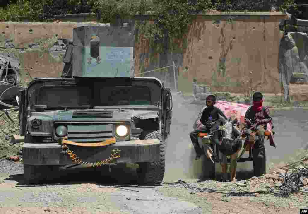 An Iraqi military vehicle passes displaced Iraqi boys returning to their homes in West Mosul&#39;s Oreibi neighborhood after government forces retook control of the area from the Islamic State (IS) group.