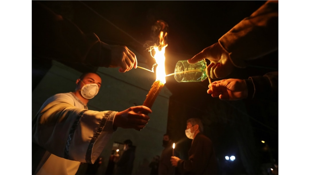 A clergyman and believers wearing protective masks hold candles outside a church during an Orthodox Easter service, amid the coronavirus disease outbreak in Marneuli, Georgia, April 19, 2020.
