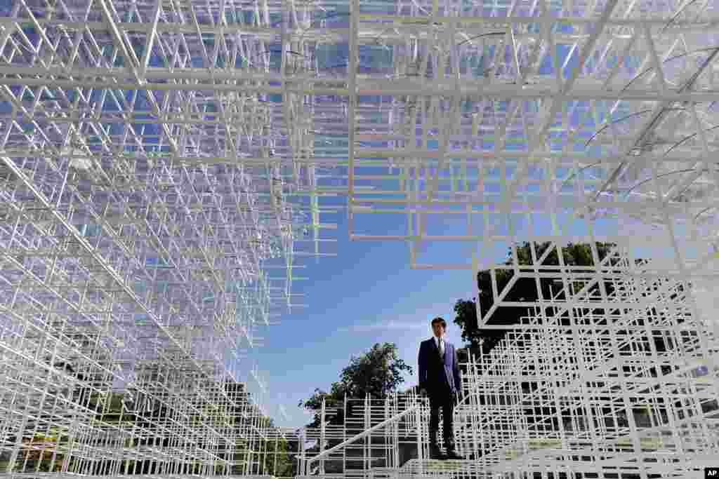 A broadcast journalist stands inside the Serpentine Gallery 2013 Pavilion, designed by Japanese architect Sou Fujimoto, in central London&#39;s Kensington Gardens. Fujimoto&#39;s structure of 20mm steel poles features a cafe and visitors will be encouraged to enter and interact with the piece in different ways.