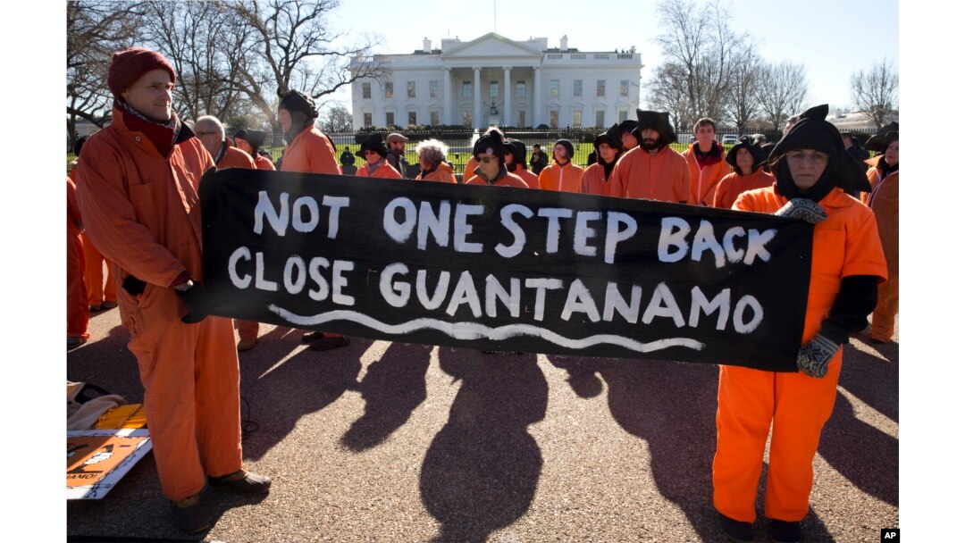 FILE - Protesters depicting Guantanamo Bay detainees hold signs calling for closing the Guantanamo Bay detention center in Cuba, at a rally at the White House in Washington, Jan. 11, 2016.