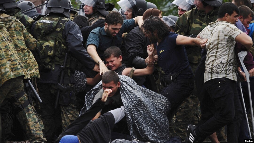 Migrants fall as they make their way through police to cross Greece's border into Macedonia near Gevgelija, Macedonia, Aug. 22, 2015. 